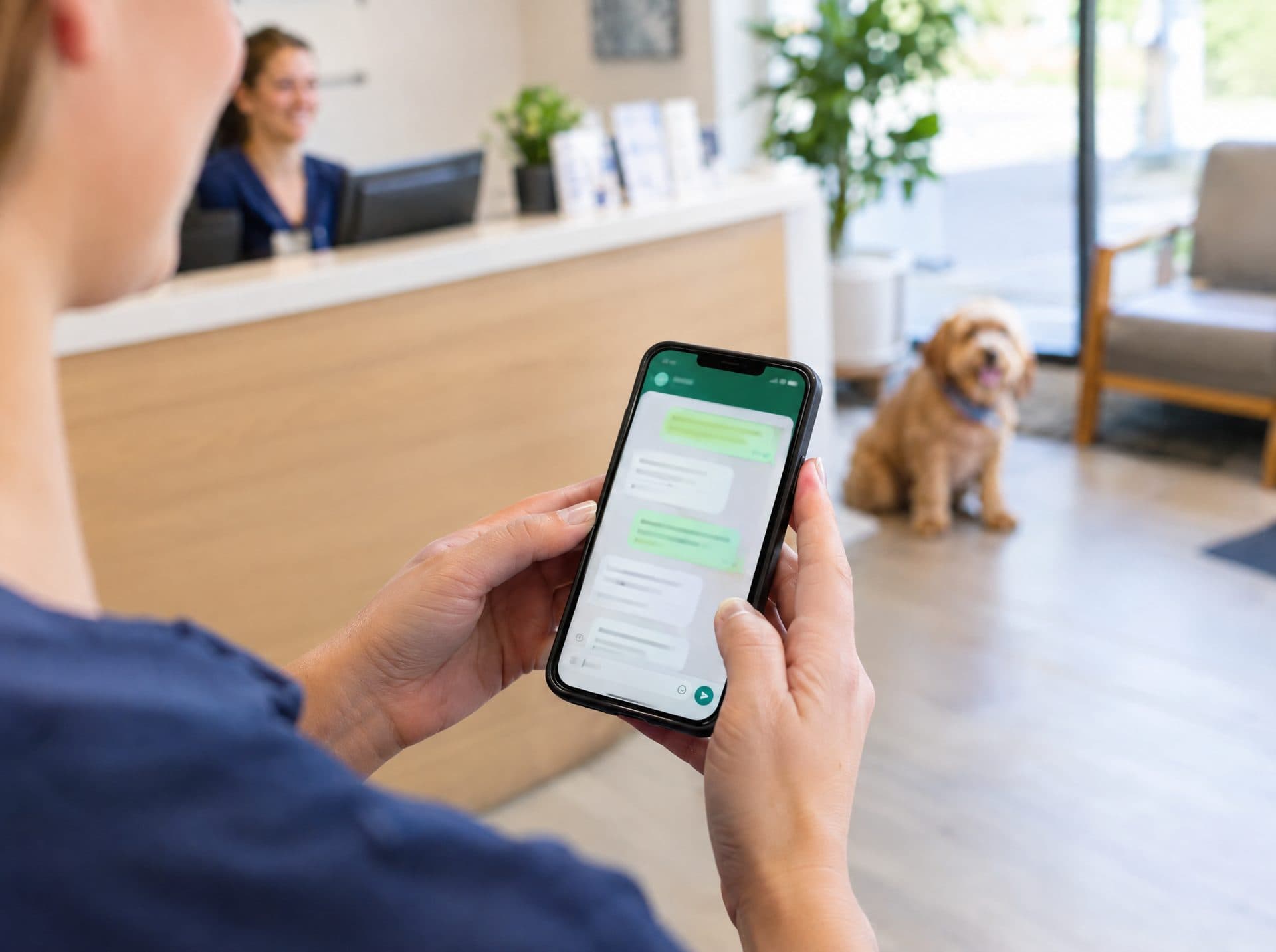Receptionist holding a phone with a WhatsApp chat open